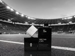 Rolă albă de Lock In Tape așezată pe cutie, pe marginea terenului de fotbal